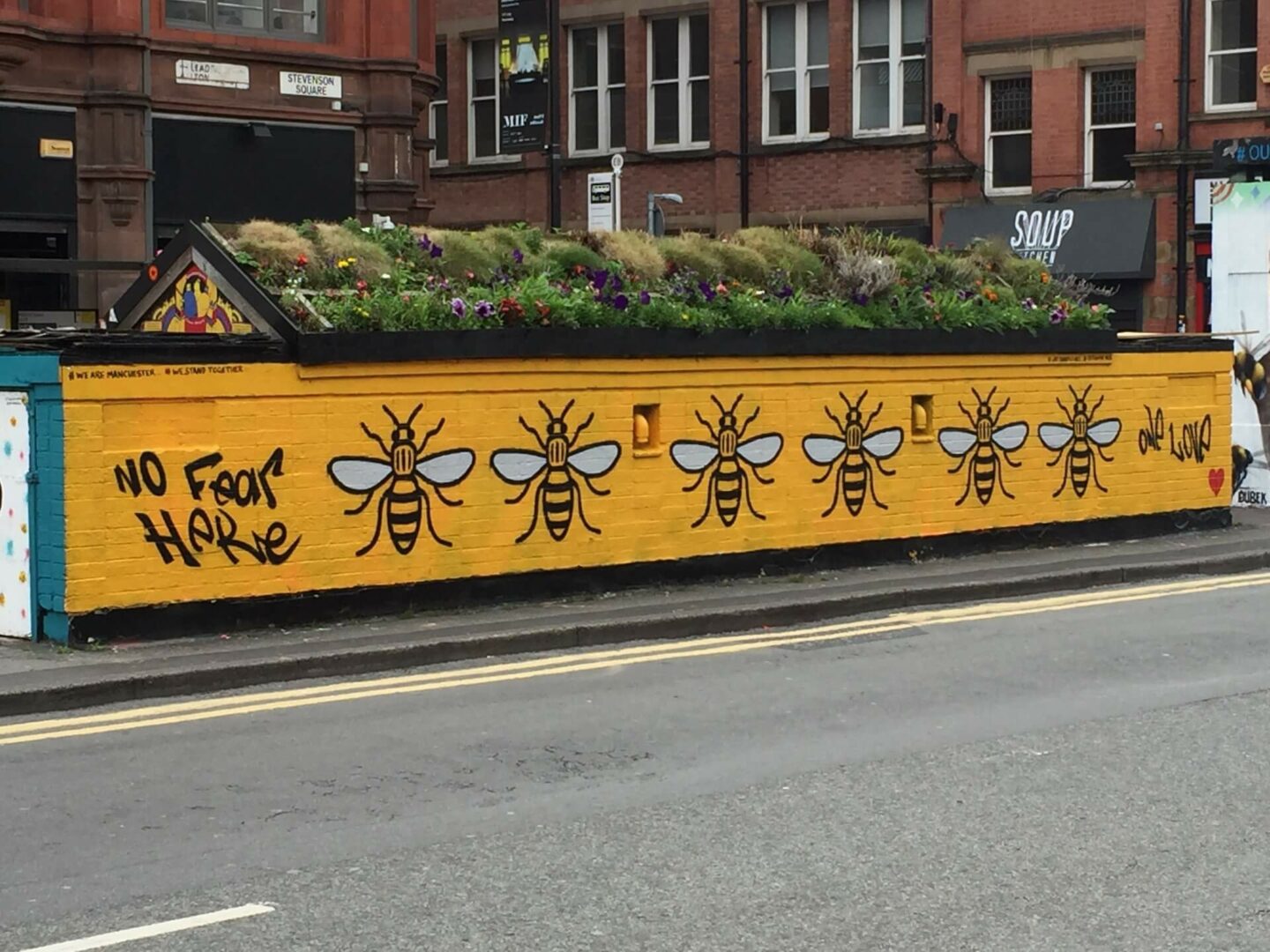 Street art in Manchester that says No Fear Here with 6 of the Manchester bee symbols